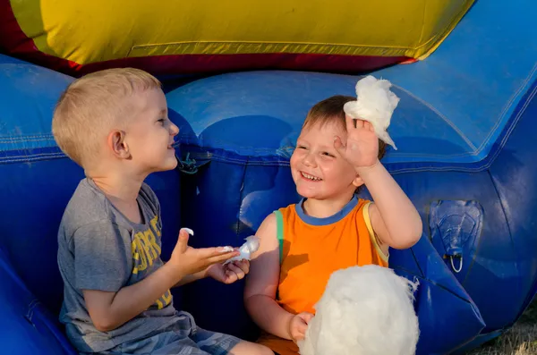 Два мальчика смеются, когда делятся сладкой ватой — стоковое фото