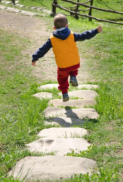 Kleiner Junge springt auf einem steinernen Fußweg — Stockfoto