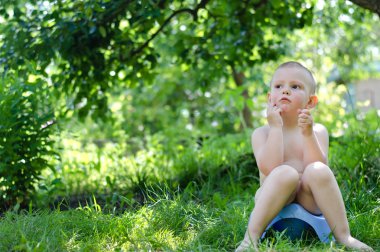 bahçede oturan gülümseyen sevimli küçük çocuk