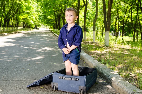 Lindo joven de pie en una maleta abierta — Foto de Stock