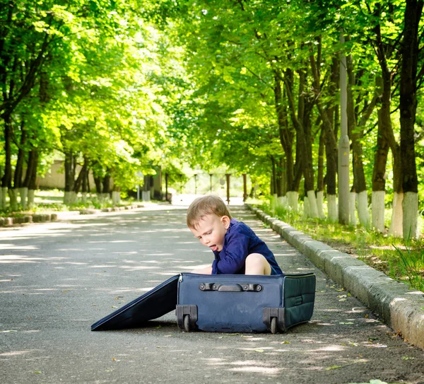 Ung pojke leker med en öppen resväska — Stockfoto