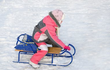 pembe bir kızak üzerinde oynayan küçük bir kız