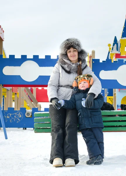 Lächelnde Mutter und Sohn auf einem Winterspielplatz — Stockfoto
