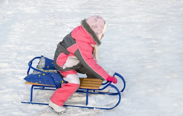 Little girl in pink playing on a toboggan — Stock Photo, Image