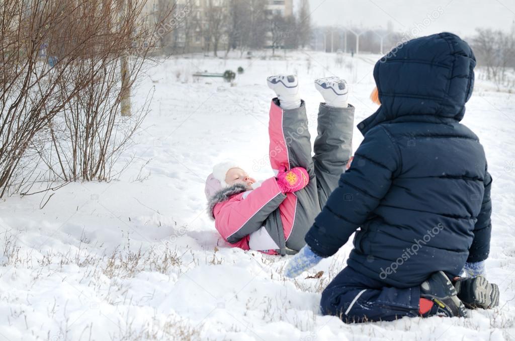 Two small children frolicking in the snow