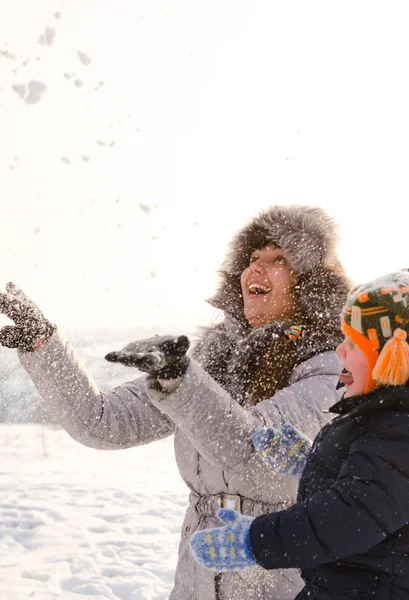 母と息子は、空気中の雪を投げを笑ってください。 — ストック写真