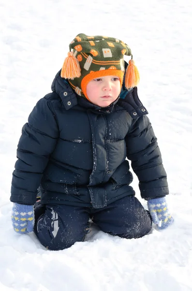 Carino piccolo ragazzo inginocchiato nella neve invernale — Foto Stock