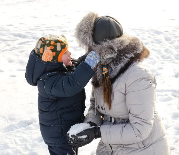 雪の中で彼の母親と一緒に遊んでかわいい男の子 — ストック写真