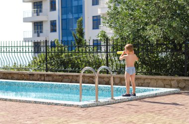 havuz kenarında duran genç çocuk