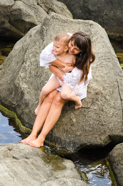 Jeune mère et son fils assis sur un rocher — Photo