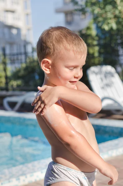 Liten pojke tillämpa sololja på hans hud — Stockfoto