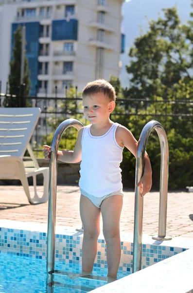 Netter kleiner Junge steht auf Schwimmbadtreppe — Stockfoto