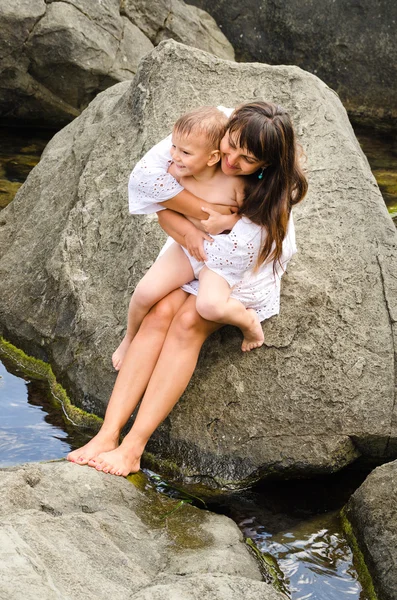 Young mother and her son sitting on a rock — Stock Photo, Image