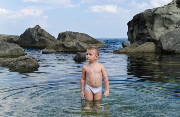 Small boy paddling in a tidal pool at the seaside