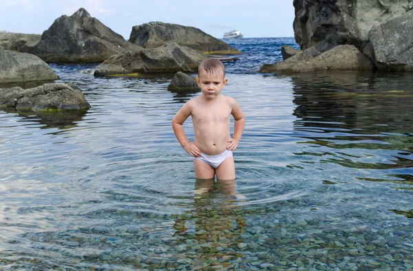 Menino pequeno remando em uma piscina de maré à beira-mar — Fotografia de Stock