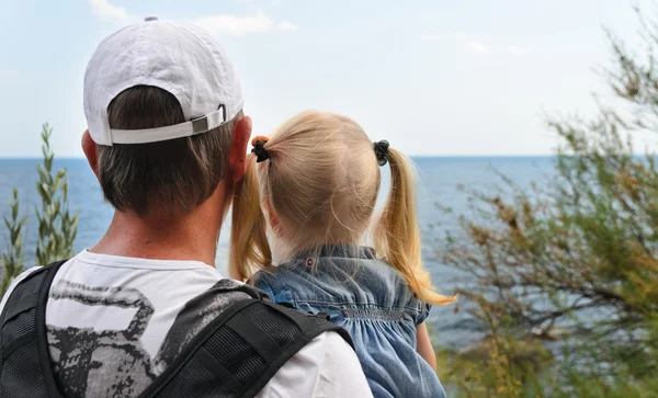 Padre sosteniendo a su hija en la orilla del mar — Foto de Stock