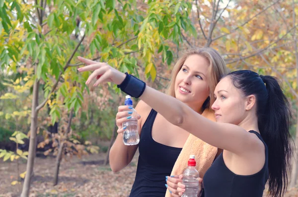 Twee passen jonge vrouwen atleten drinkwater — Stockfoto