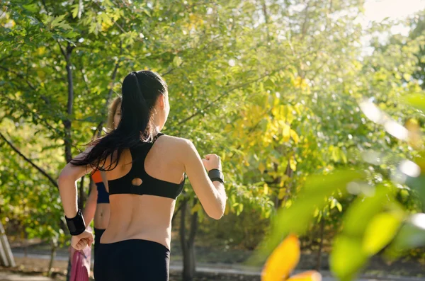 Passar ung kvinna jogging genom en solig park — Stockfoto