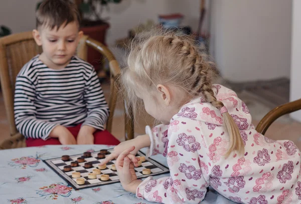 Jong meisje en jongen samenspelen dammen — Stockfoto