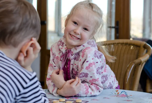 Beautiful little girl playing a game of checkers — Stock Photo, Image