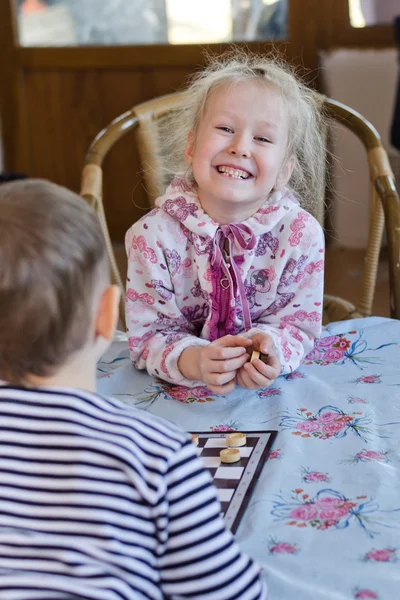 Beautiful laughing little girl playing checkers — Stock Photo, Image