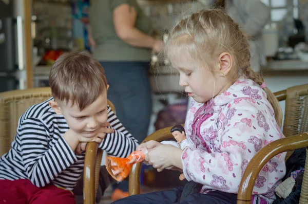 Glad liten flicka och en pojke som leker med en docka — Stockfoto