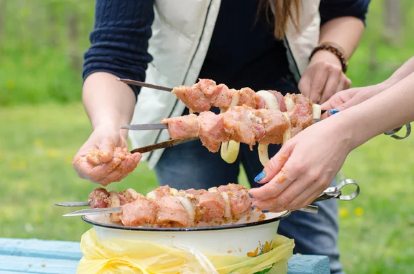 Woman preparing kebabs to grill on a BBQ — Stock Photo, Image
