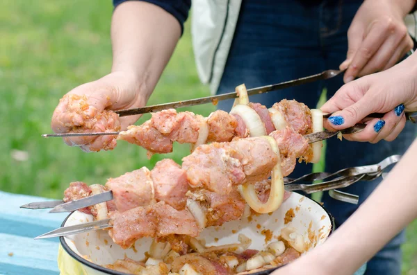 Woman preparing kebabs to grill on a BBQ — Stock Photo, Image