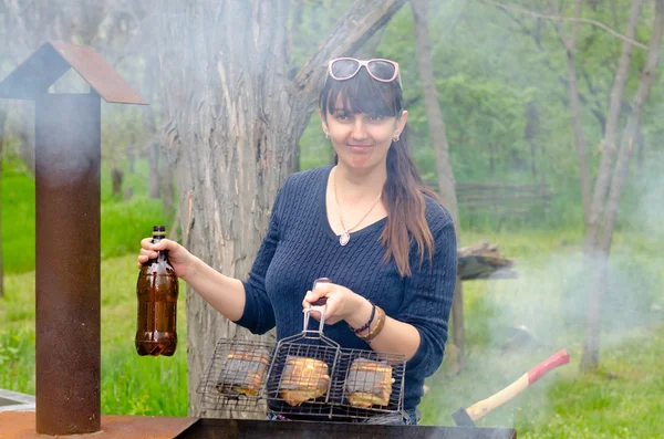 Lächelnde Frau, die draußen über einem Grill kocht — Stockfoto