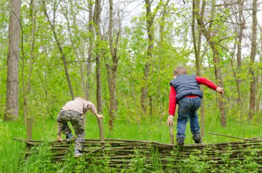 Two young boys playing on a rustic fence clipart