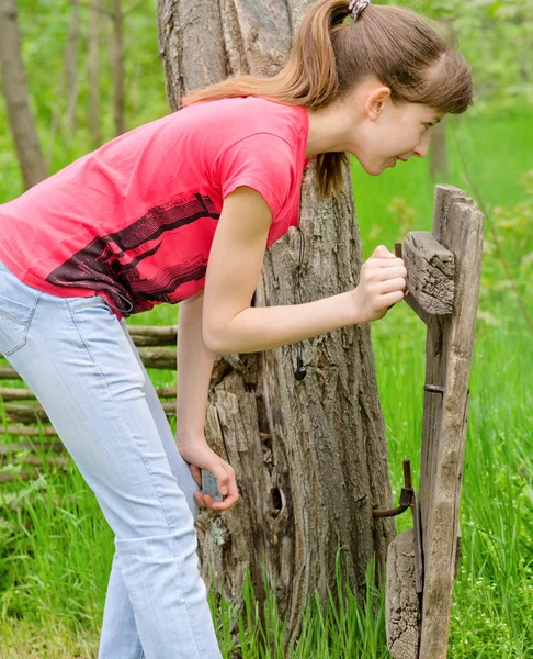 Teenager-Mädchen beobachtet ein altes, baufälliges Holztor — Stockfoto