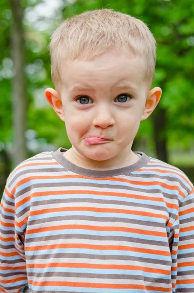 Carino giovani ragazzo tirando un divertente espressione — Foto Stock