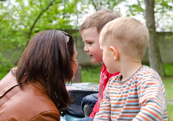 Atractiva joven mujer charlando con dos niños pequeños — Foto de Stock