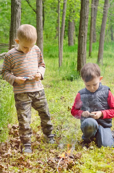 Two small boys lighting a fire in woodland — Stock Photo, Image