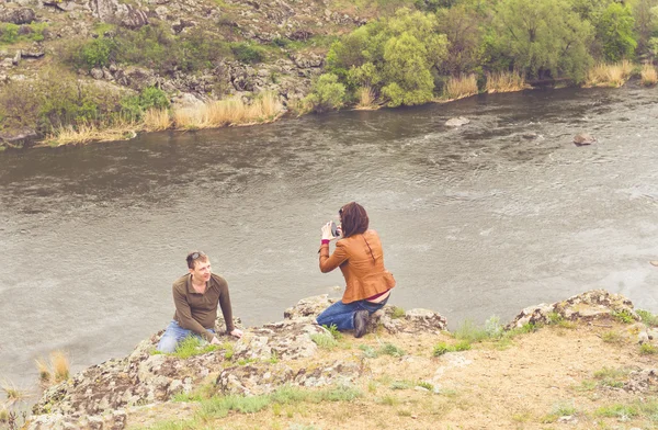 Ung kvinna fotografera en man på en bergstopp — Stockfoto