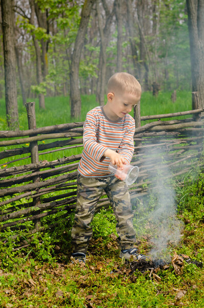 Little boy putting out a camp fire
