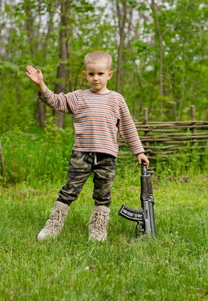 Niño llevando una ametralladora saludando —  Fotos de Stock