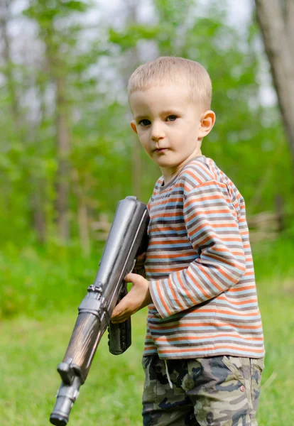 Schattige jongen gericht met machine gun — Stockfoto