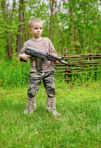 Selamlayan bir makineli tüfek taşıyan çocuk — Stok fotoğraf