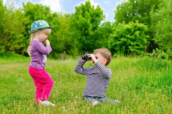 Klein meisje en jongen speelt met een verrekijker — Stockfoto