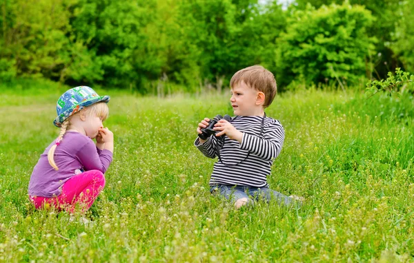 Klein meisje en jongen speelt met een verrekijker — Stockfoto