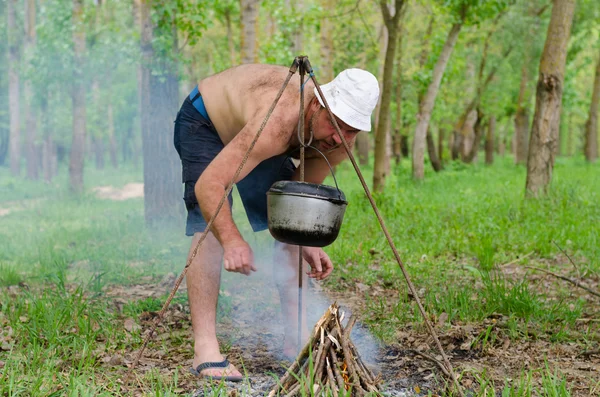 Homme allumant un feu de cuisson dans un camping — Photo