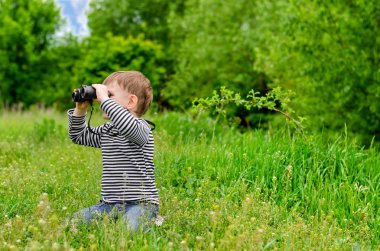 küçük çocuk kameraya dürbünle bakıyor