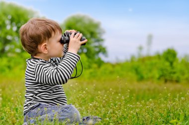 Little boy looking at the camera with binoculars clipart