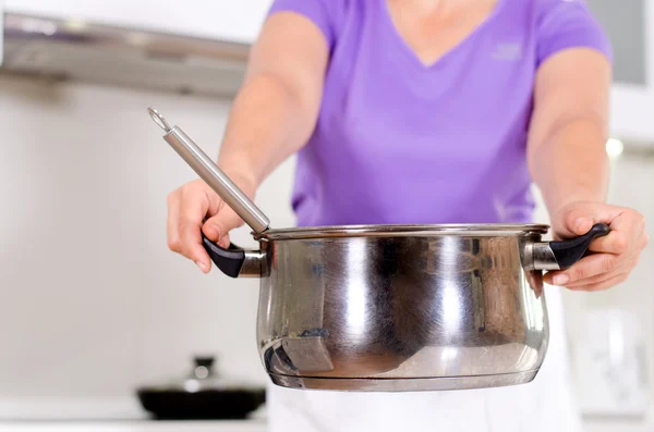 Woman holding out a metal saucepan — Stock Photo, Image