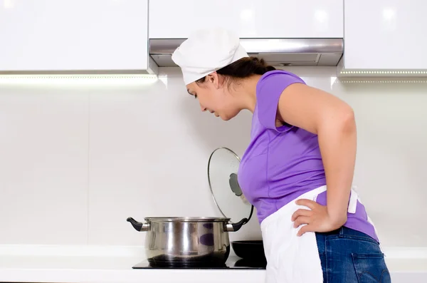 Köchin sieht einem Topf beim Kochen zu — Stockfoto