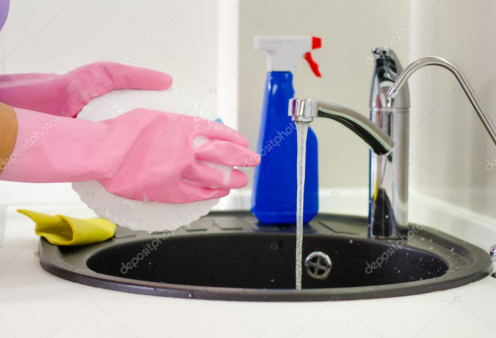 Woman rinsing plates under the tap