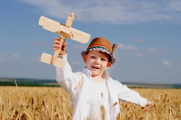 Junge spielt mit Flugzeug auf einem Feld — Stockfoto