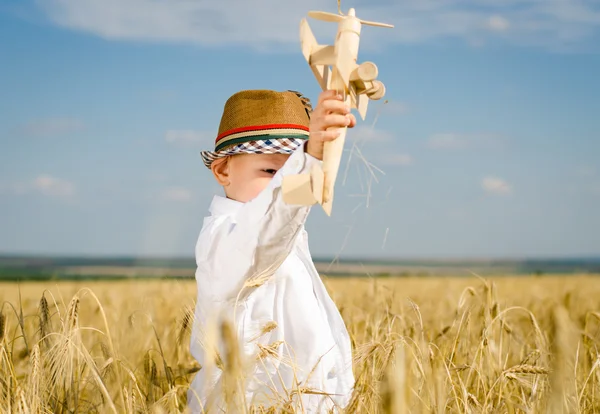 Liten pojke flyger en leksak plan i ett vete fält — Stockfoto