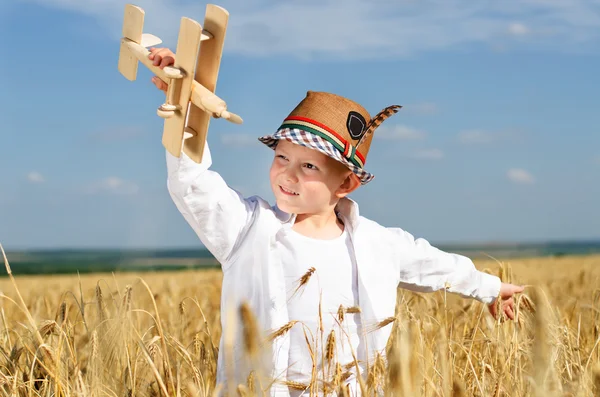 Trendy young boy playing in a field with a plane — Stock Photo, Image